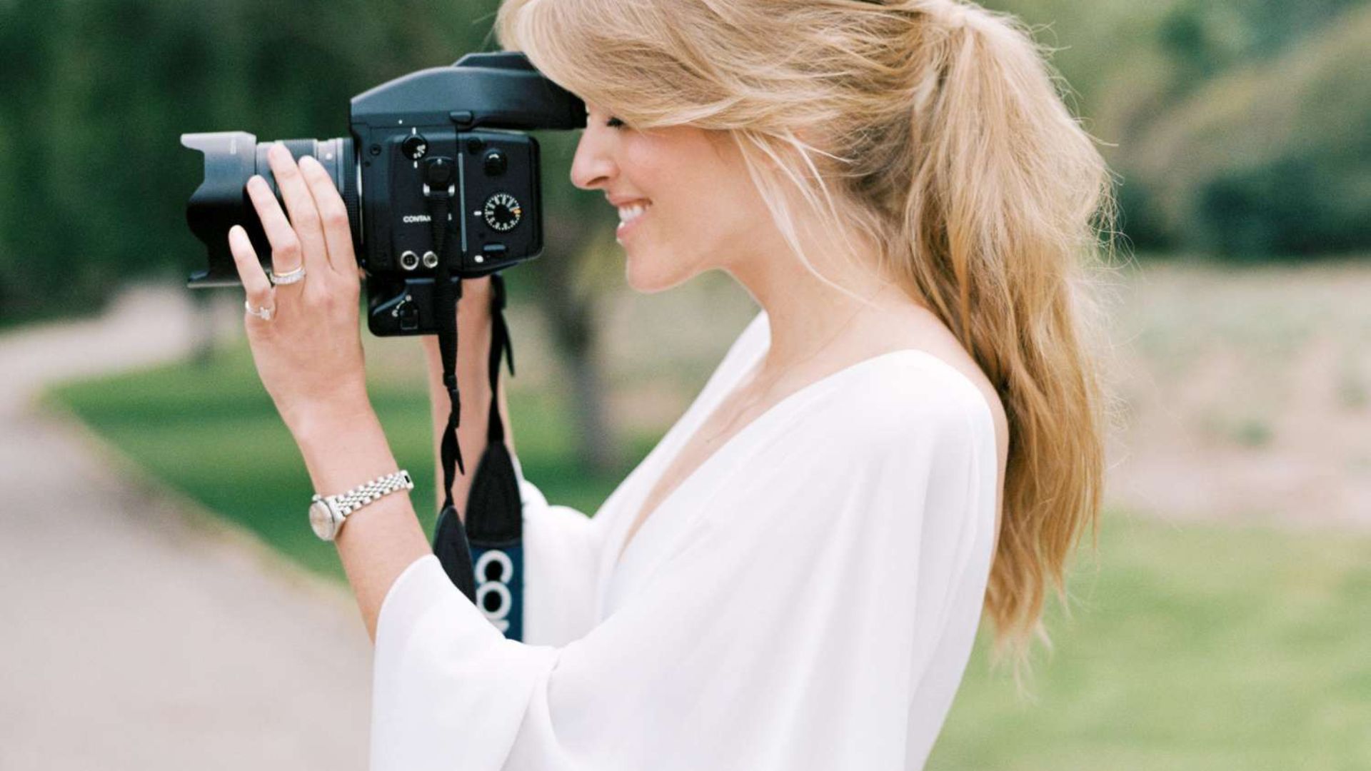 a lady wearing a white blouse taking a photography showing pgotography genres