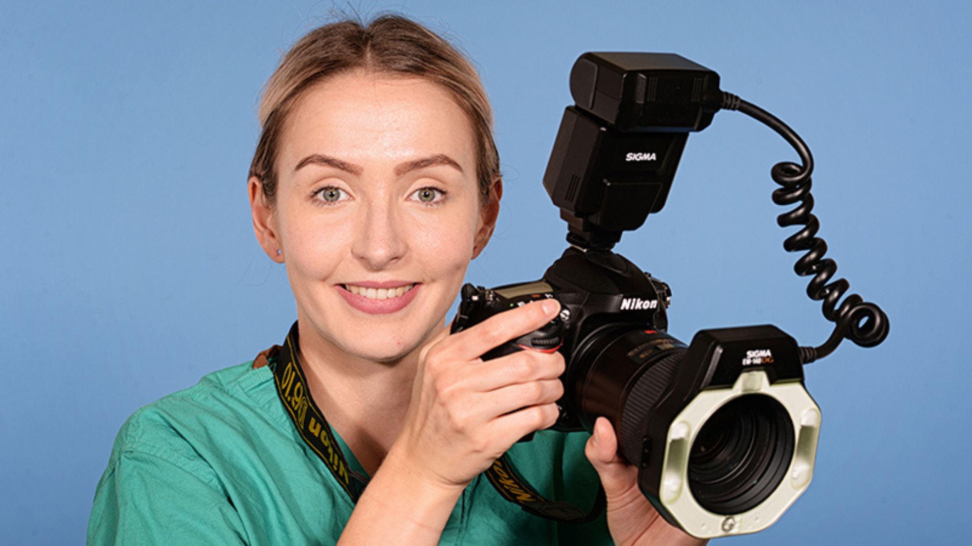 a female doctor smiling while hoding a camera